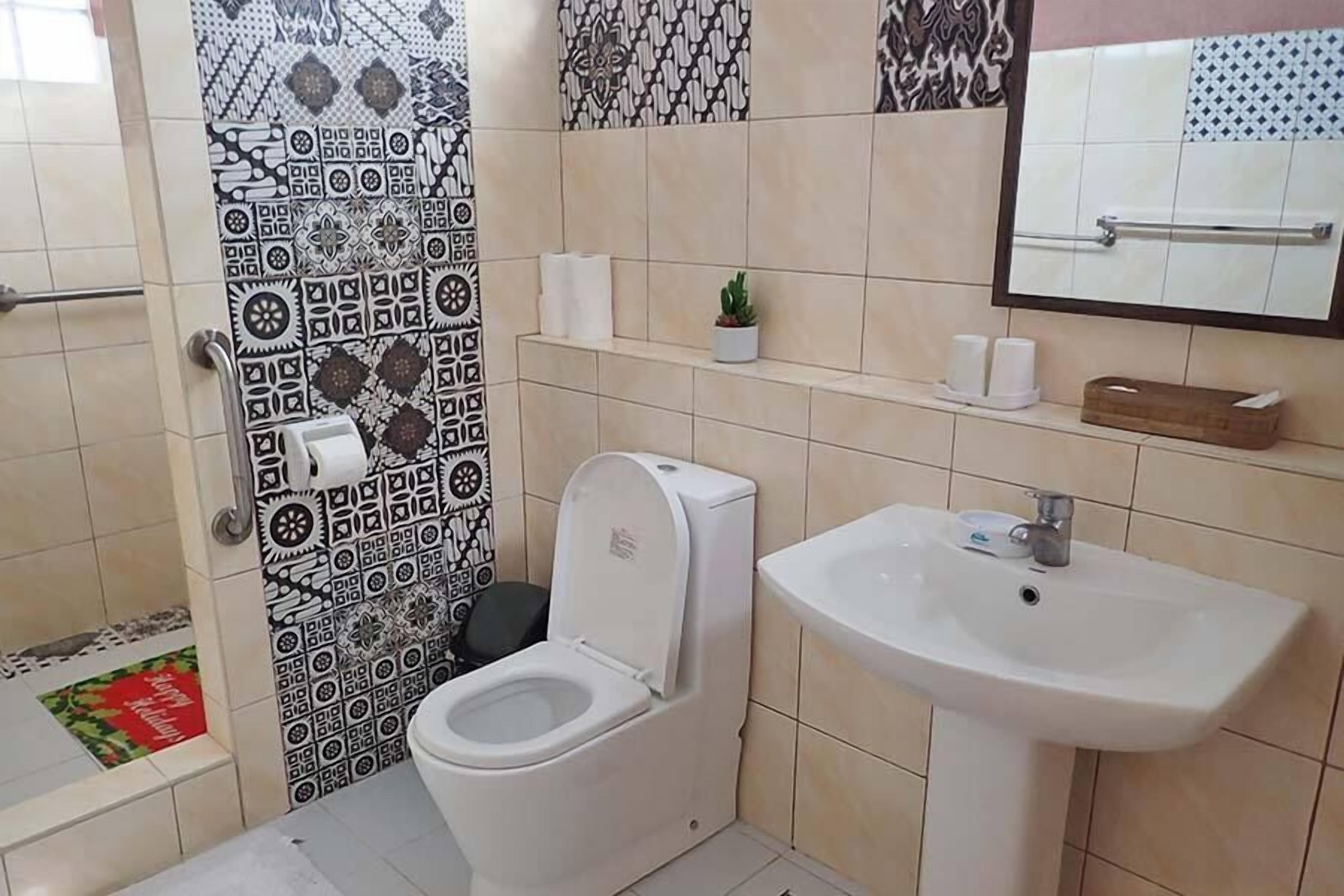Un baño con baldosas estampadas, un inodoro, un lavabo y un espejo.