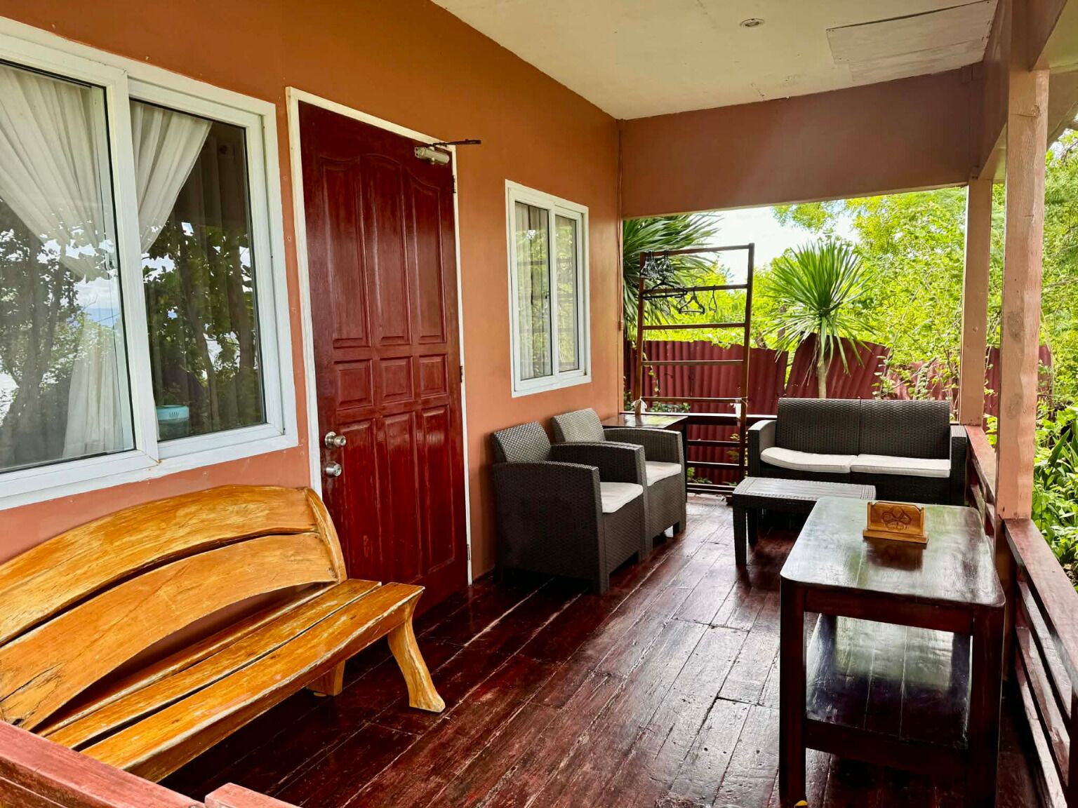 A covered porch with a wooden bench, wicker furniture, and a small table.