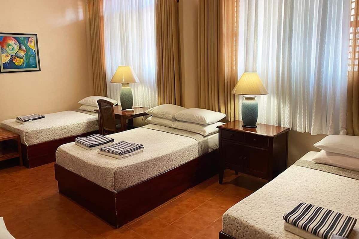 A hotel room with two single beds, a wooden nightstand, a desk, and a chair.