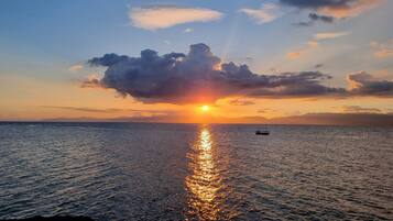 A sunset over a calm sea with a boat in the distance.