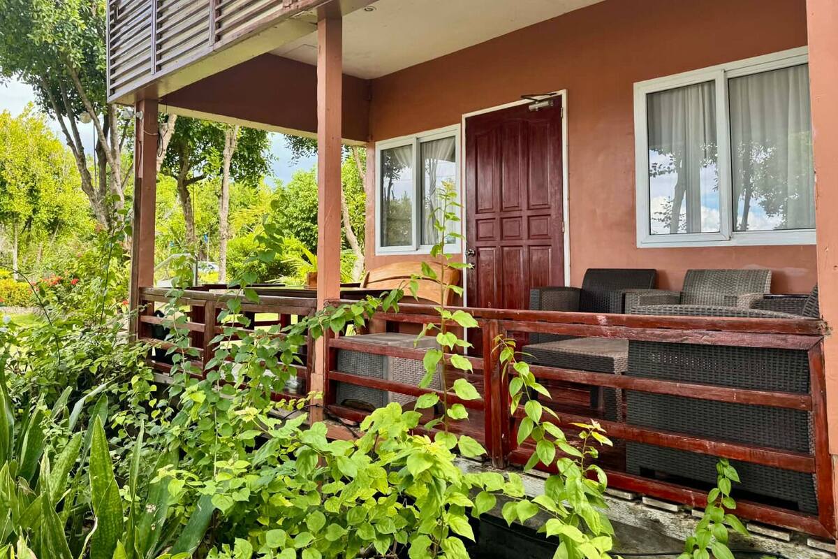 A covered outdoor seating area with wooden benches and a red door.