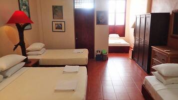 Quarto de hotel com duas camas, televisão, guarda-roupa e janela com cortinas.