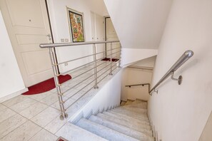 A staircase with a metal handrail, marble steps, and a red carpet at the bottom.
