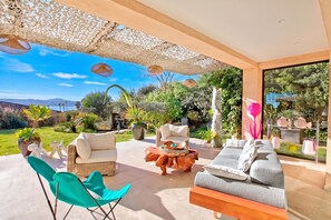 A spacious outdoor seating area with a view of the sea, furnished with a sofa, chairs, and a coffee table.