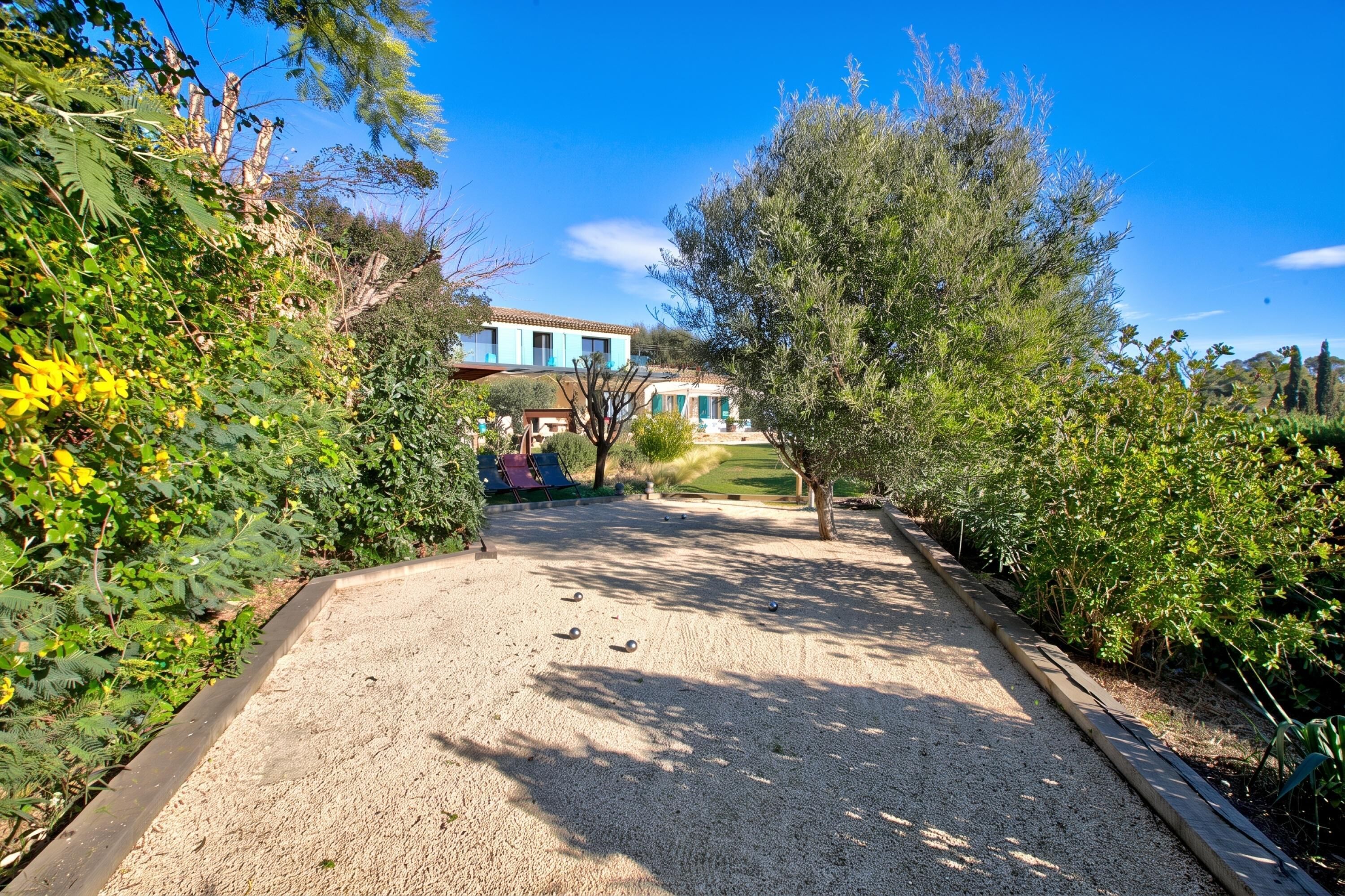 A gravel courtyard with a building in the background, surrounded by greenery.