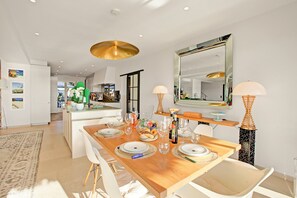 A modern dining area with a wooden table set for four, white chairs, and a large mirror above. - Villa Bayugita, Grimaud, France (Grimaud)