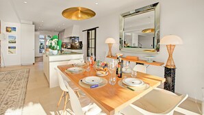 A modern dining area with a wooden table set for four, white chairs, and a large mirror above. - Villa Bayugita With Master Bedroom, Grimaud, France (Grimaud)