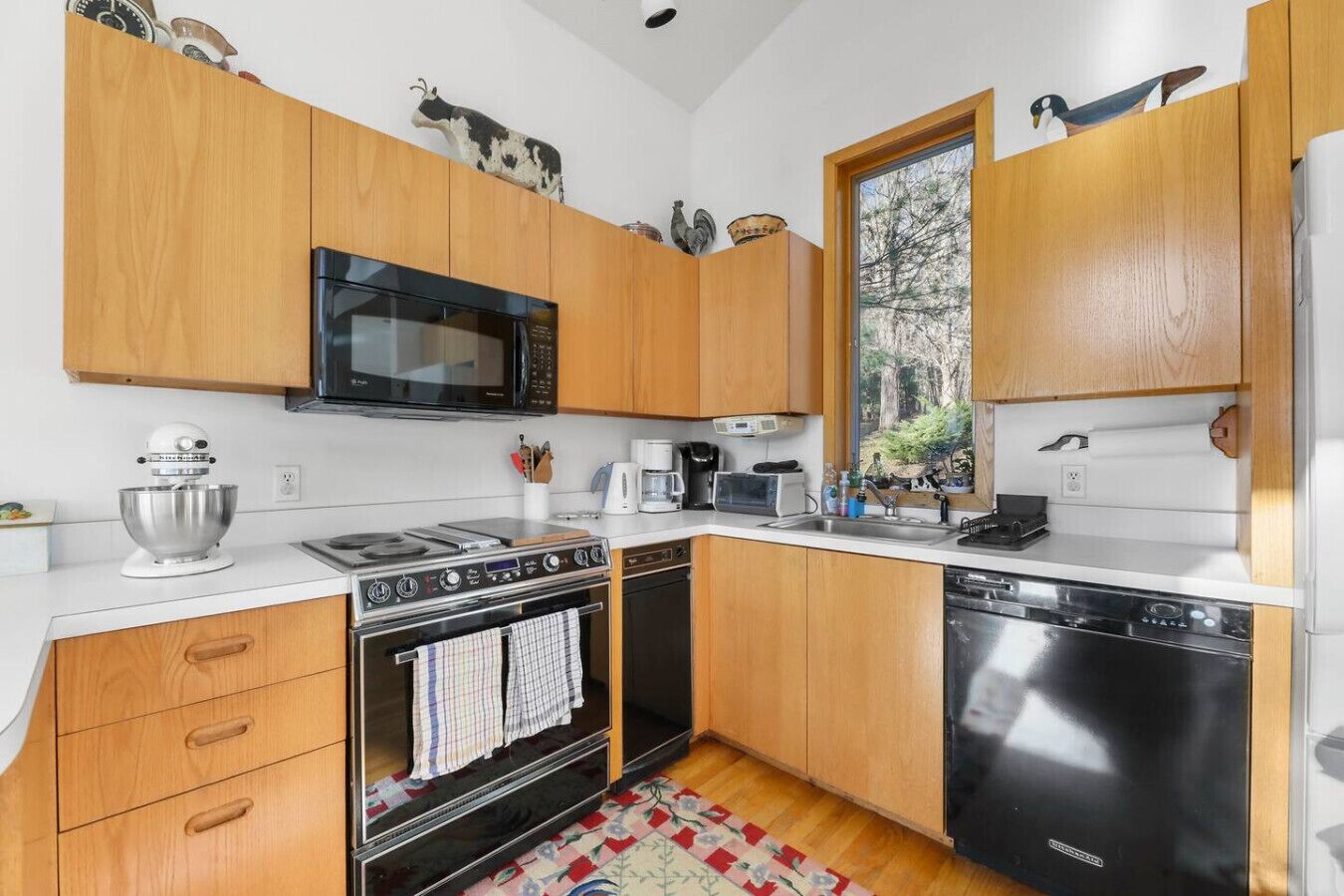 A modern kitchen with wooden cabinets, a microwave, stove, oven, and dishwasher.