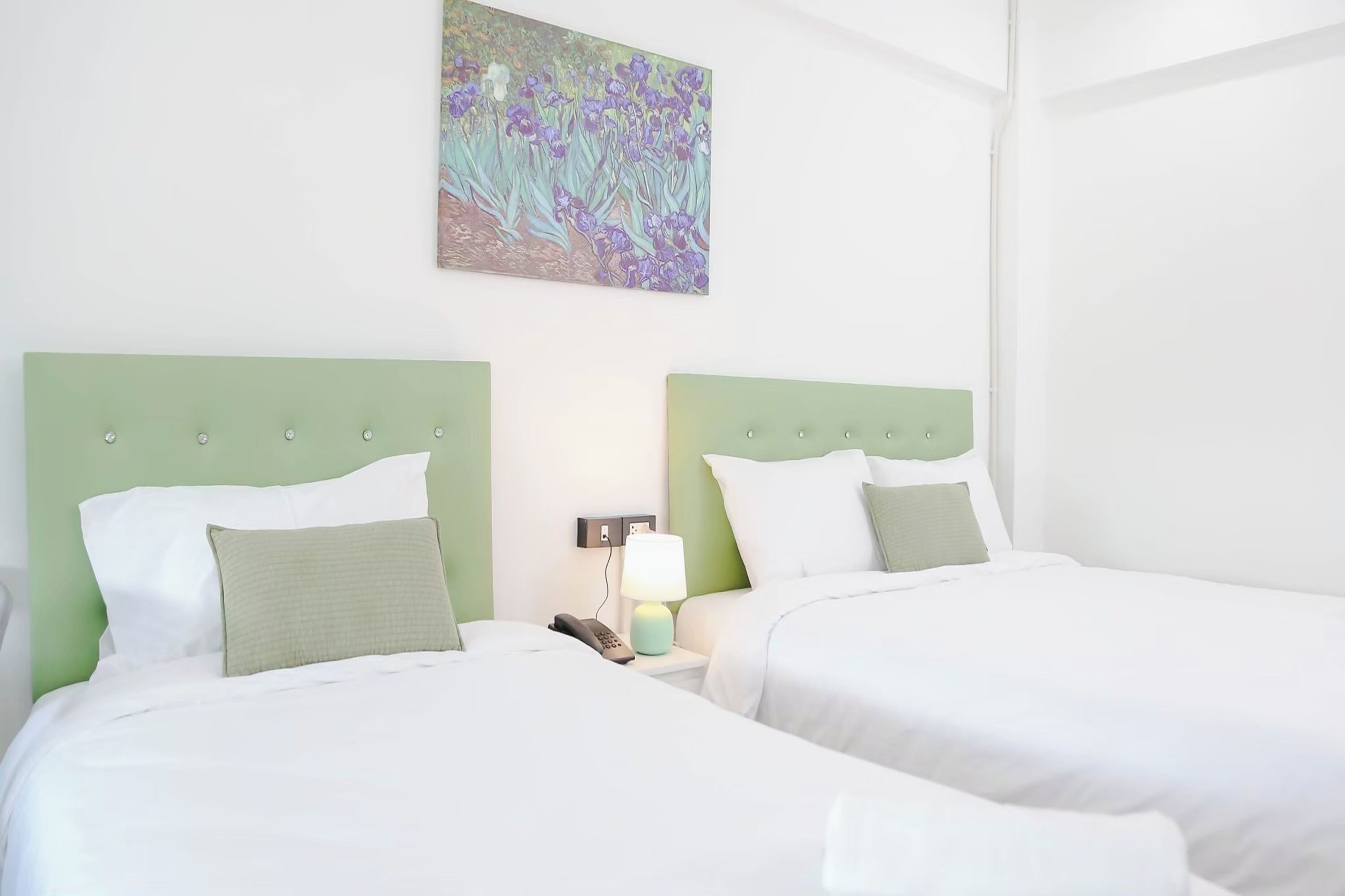 Une chambre d’hôtel avec deux lits, une table de chevet avec une lampe et un tableau au mur.