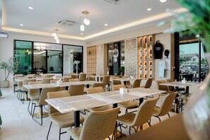 Un comedor moderno con mesas y sillas, una pared de vidrio y vistas al exterior.