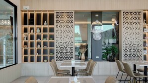 A modern dining area with a central table, surrounded by chairs, and shelves with decorative items. - Chana Bangkok Hotel (Bangkok)