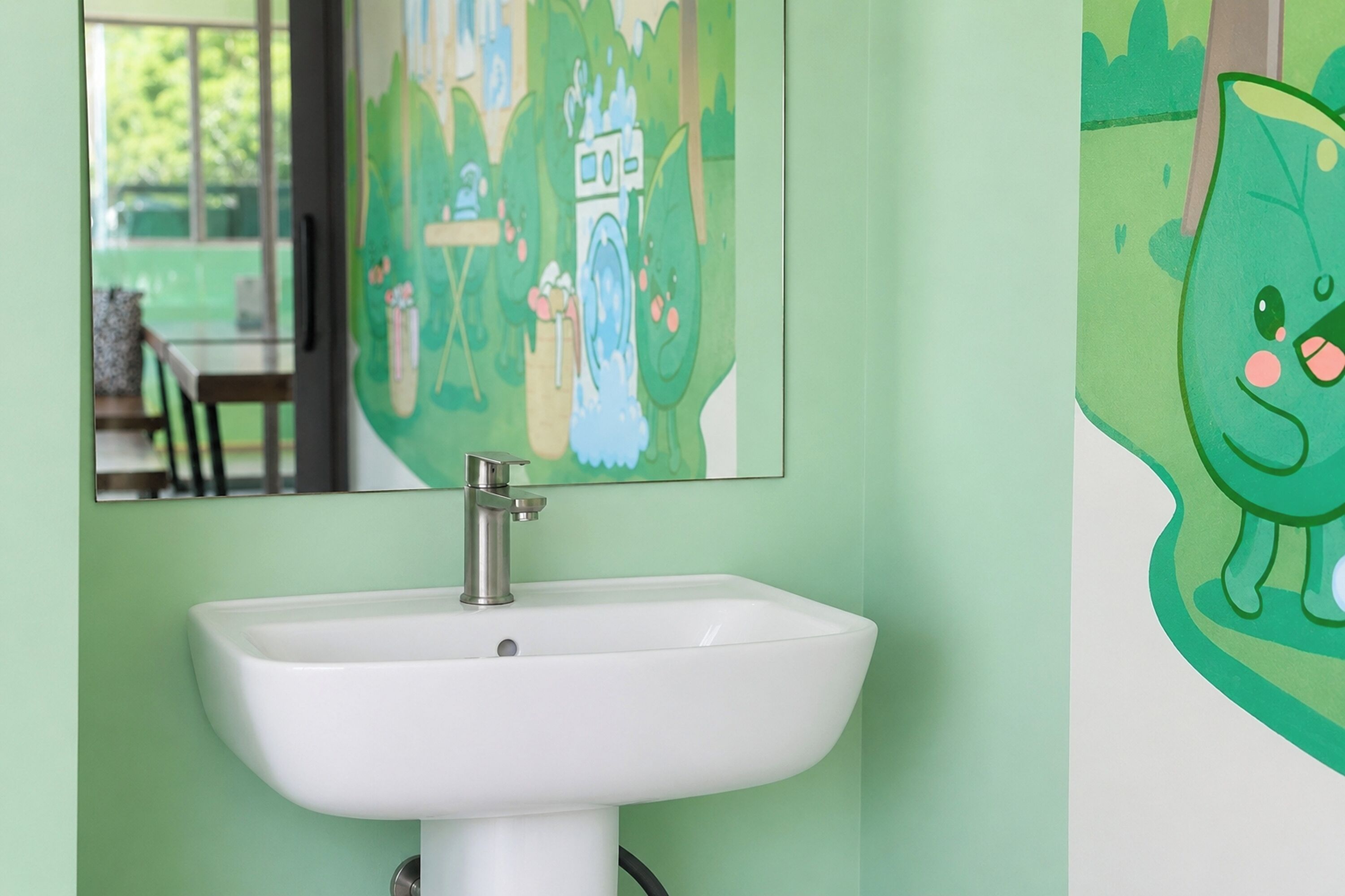 A bathroom with a white sink, a mirror, and a green wall.