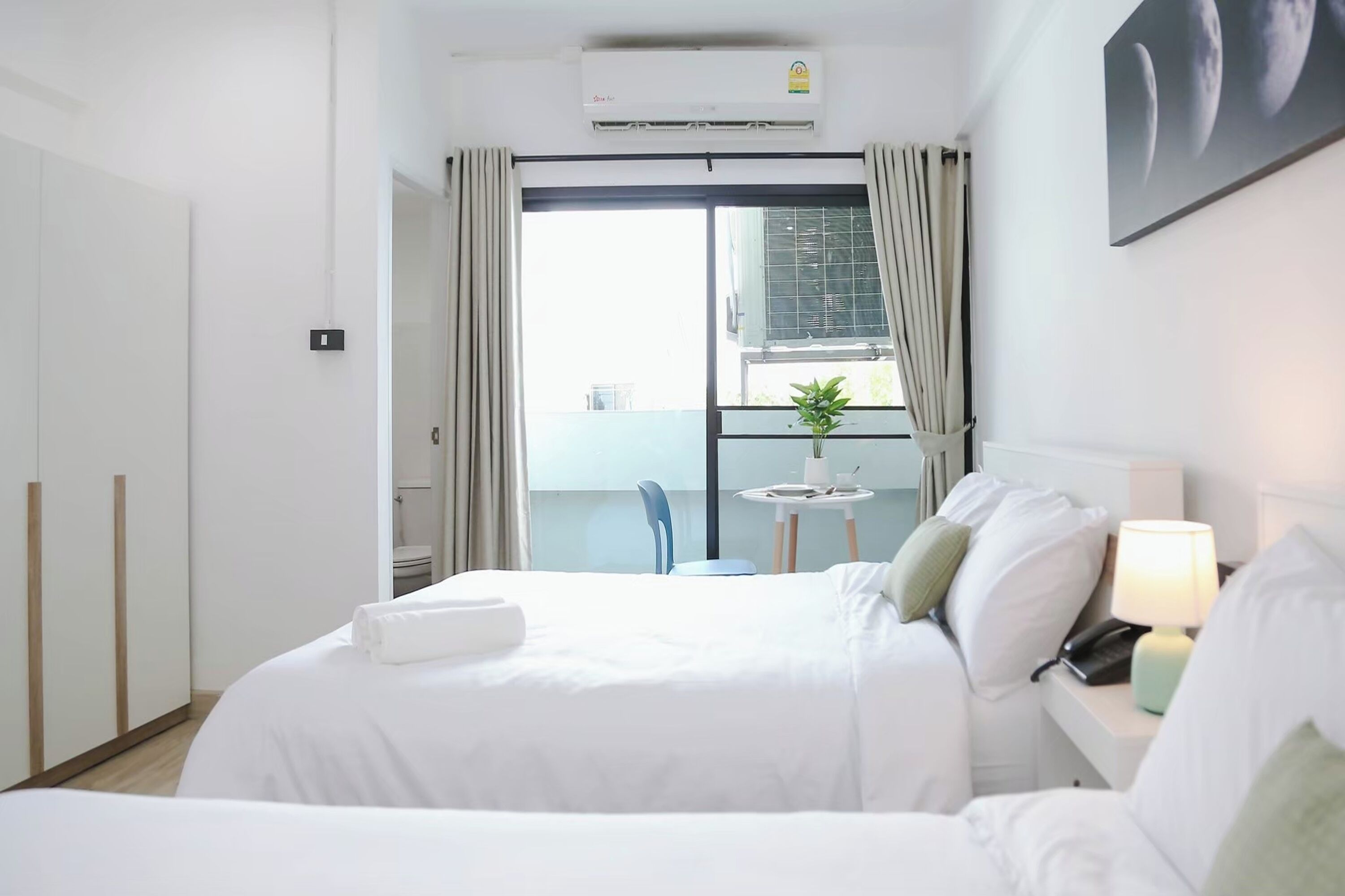 Hotellihuone, jossa on sänky, yöpöytä, lamppu ja näkymä parvekkeelle.