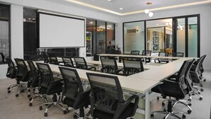 A conference room with a long table, multiple chairs, a projector screen, and glass walls. - Chana Bangkok Hotel (Bangkok)