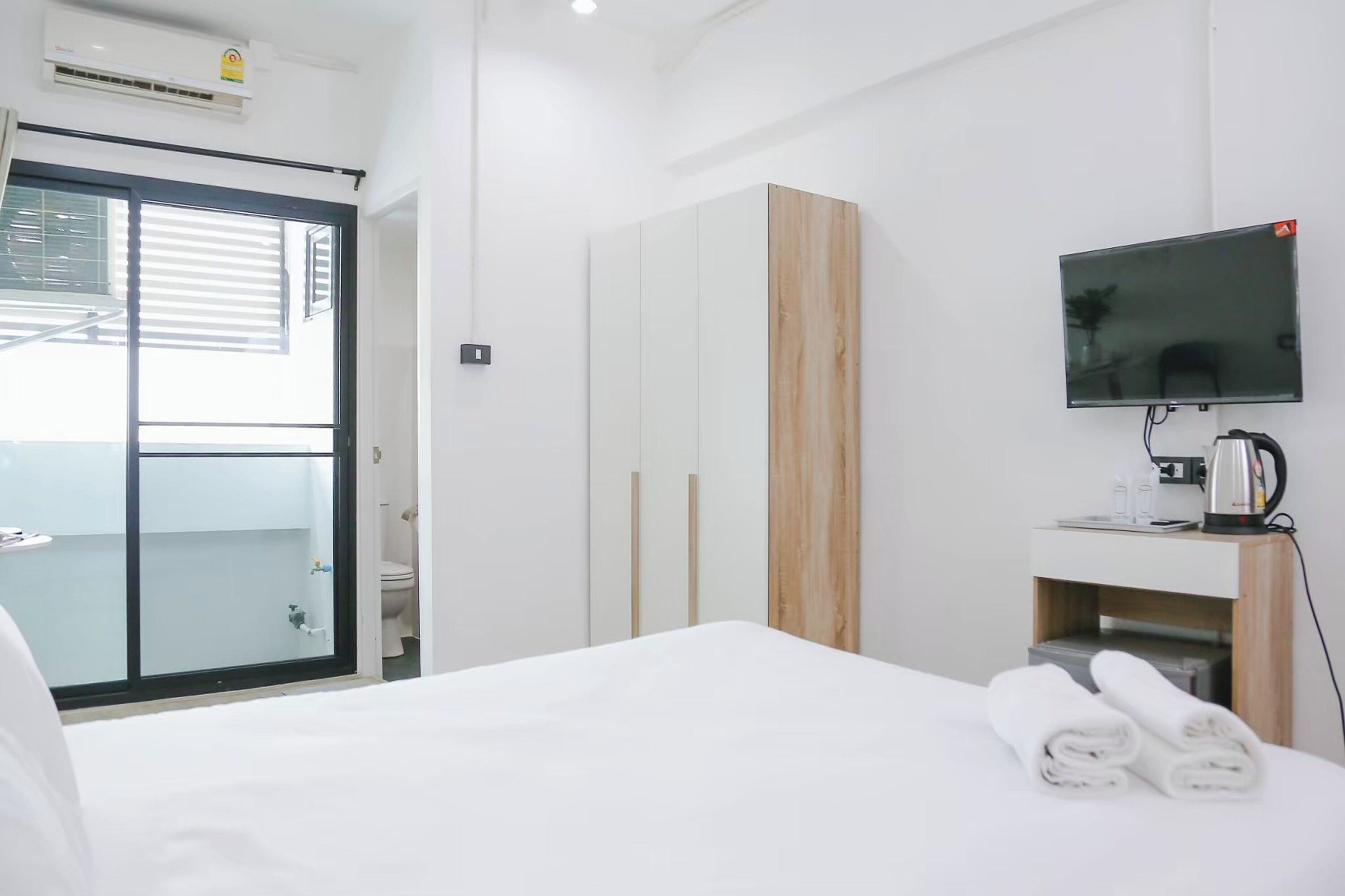 A hotel room with a bed, a TV, a coffee machine, and a view of the outside.