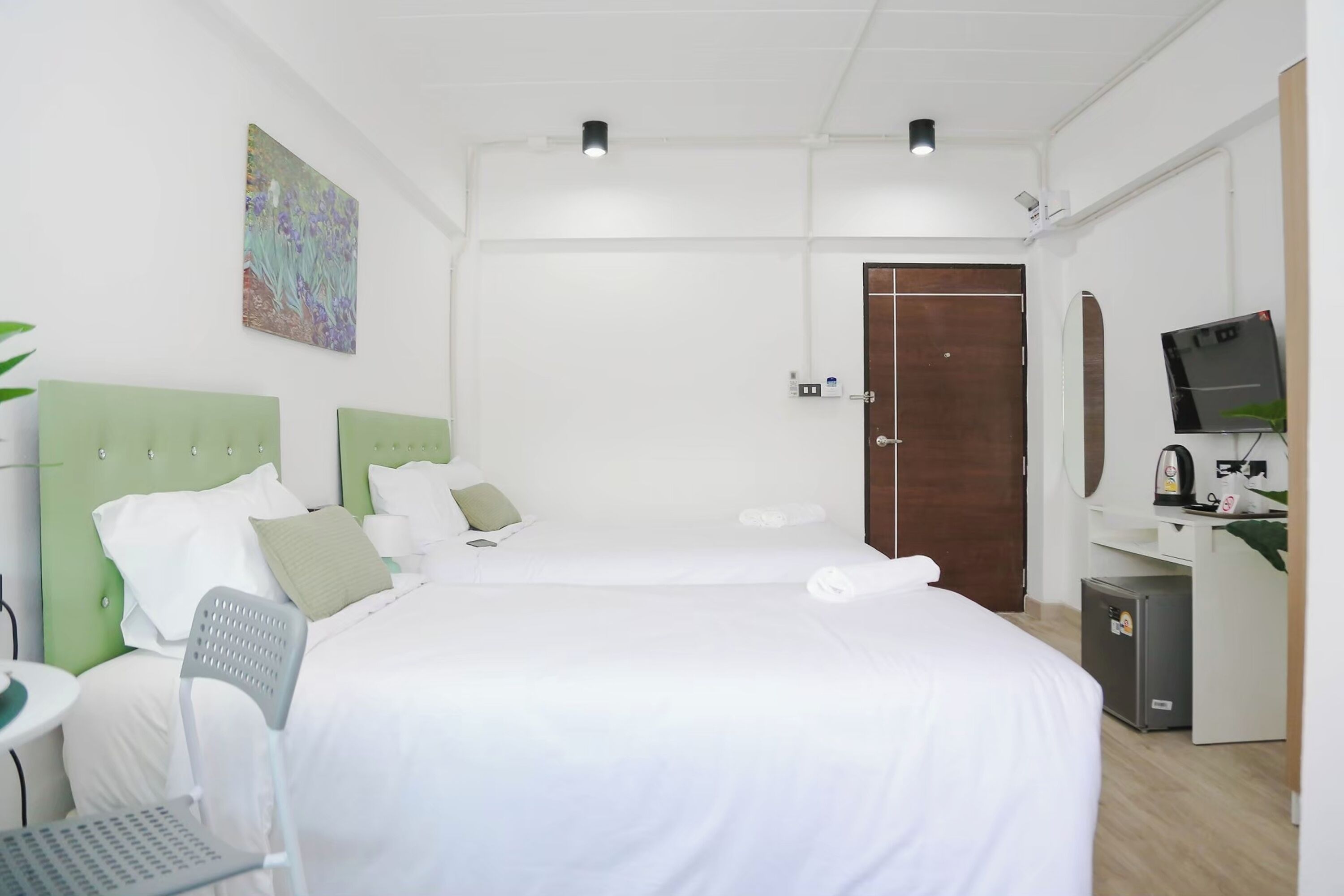 Ein Hotelzimmer mit zwei Betten, einem Schreibtisch, einem Stuhl, einem Fernseher und einem kleinen Kühlschrank.