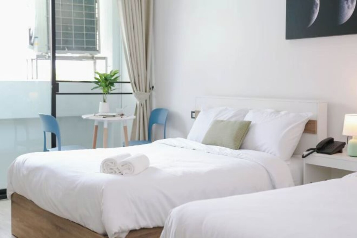 Une chambre d’hôtel avec un lit, un bureau, une chaise et une petite table sur laquelle est posée une plante.