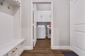 A laundry room with a washing machine and dryer, wooden flooring, and white cabinetry.