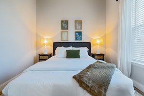 A neatly made bed with white linens, two bedside lamps, and a decorative throw blanket.