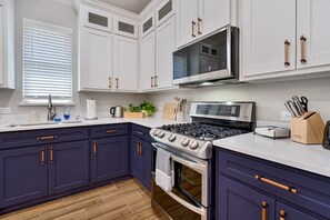 A modern kitchen with white upper cabinets, dark lower cabinets, a gas stove, and a microwave.