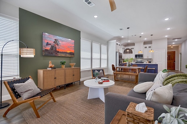 A modern living room with a sofa, a coffee table, and a dining area with a bench.