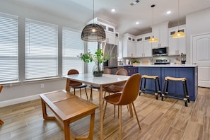 A modern kitchen with white cabinets, a central island, and pendant lighting.