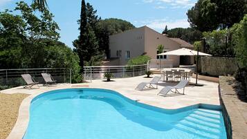 Relax by the serene pool surrounded by lounge chairs and lush greenery.