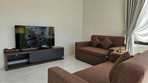 A modern living room with a flat-screen TV, a brown sofa, and a wooden entertainment unit. - Baan First Pool Villa (Koh Samui)