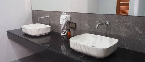 Un baño moderno con dos lavamanos de mármol, un espejo grande y una encimera oscura.