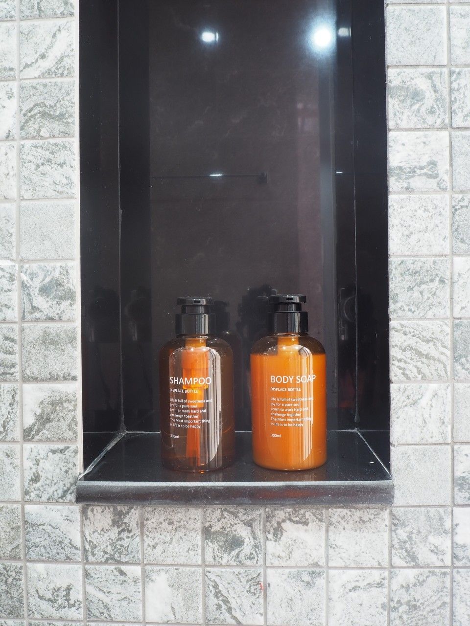 Two bottles of shampoo and body soap in a bathroom sink.
