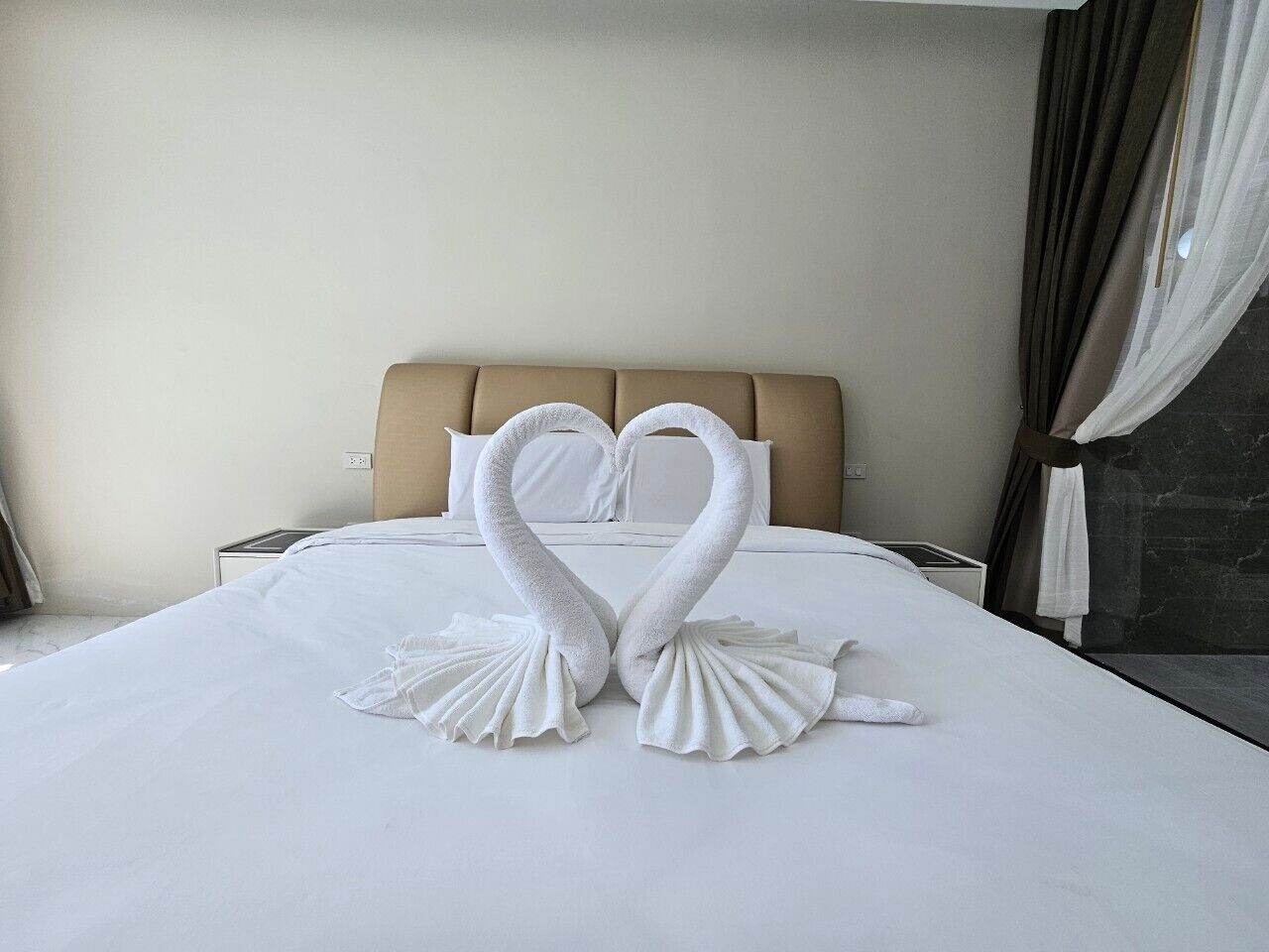 Une chambre d’hôtel avec un lit agrémenté d’une décoration en serviettes représentant deux cygnes.