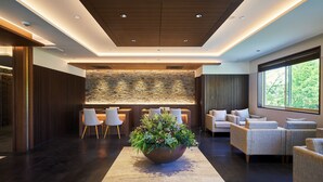 Un vestíbulo moderno con pared de piedra, zona de estar y un gran centro de mesa con plantas.