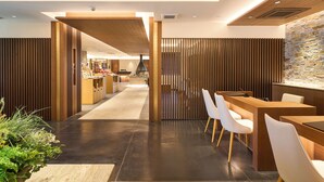 Un moderno vestíbulo de hotel con mostrador de recepción, zona de estar y vistas al comedor.