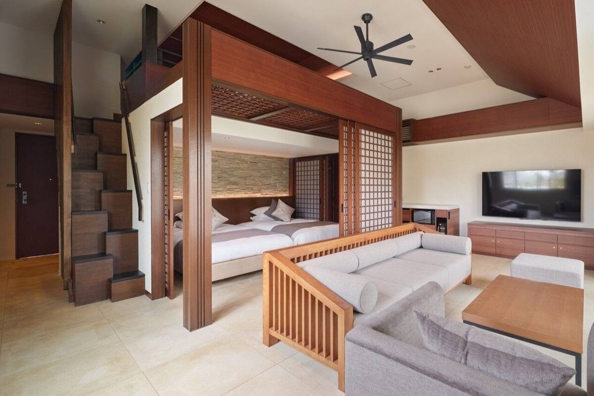 Ein modernes Wohnzimmer mit Sofa, Couchtisch, Fernseher und einer Treppe.