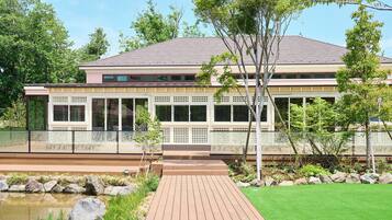 A modern house with a large deck, a pond, and a well-maintained lawn.