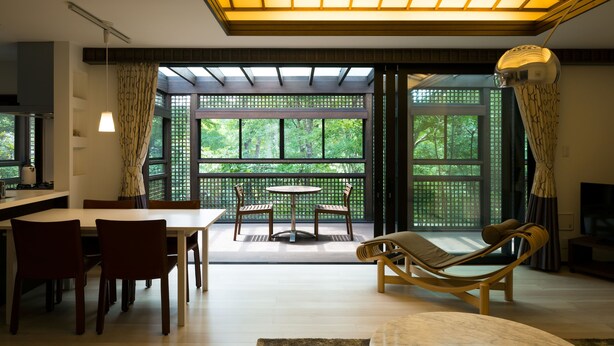 Una sala de estar moderna con comedor, ventanas grandes y una lámpara de techo.