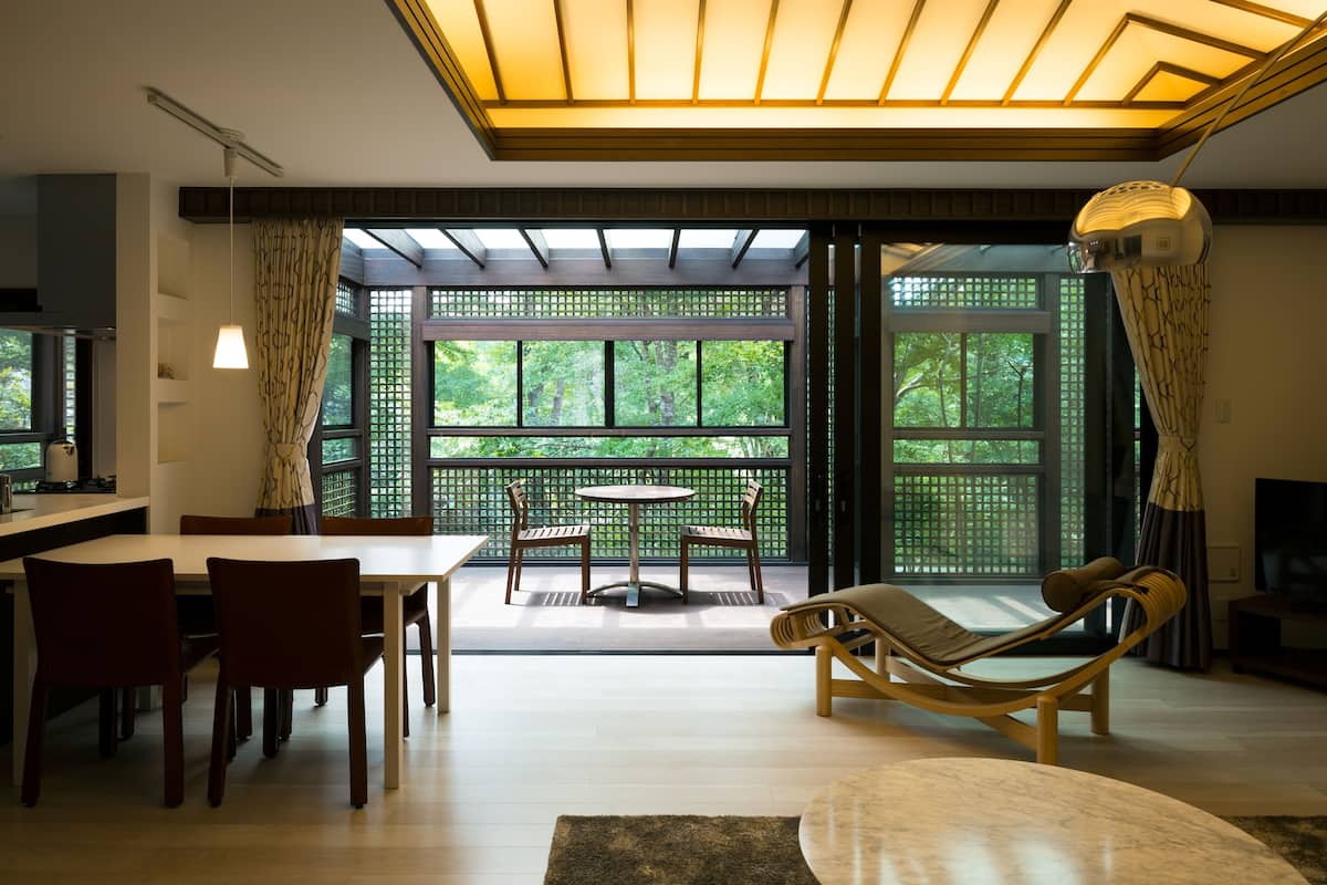 Ein modernes Wohnzimmer mit Essbereich, großen Fenstern und einer Deckenleuchte.