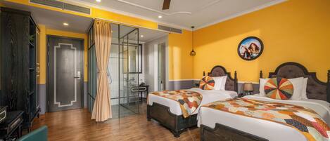 A hotel room with two beds, a ceiling fan, a large window with curtains, and a television.