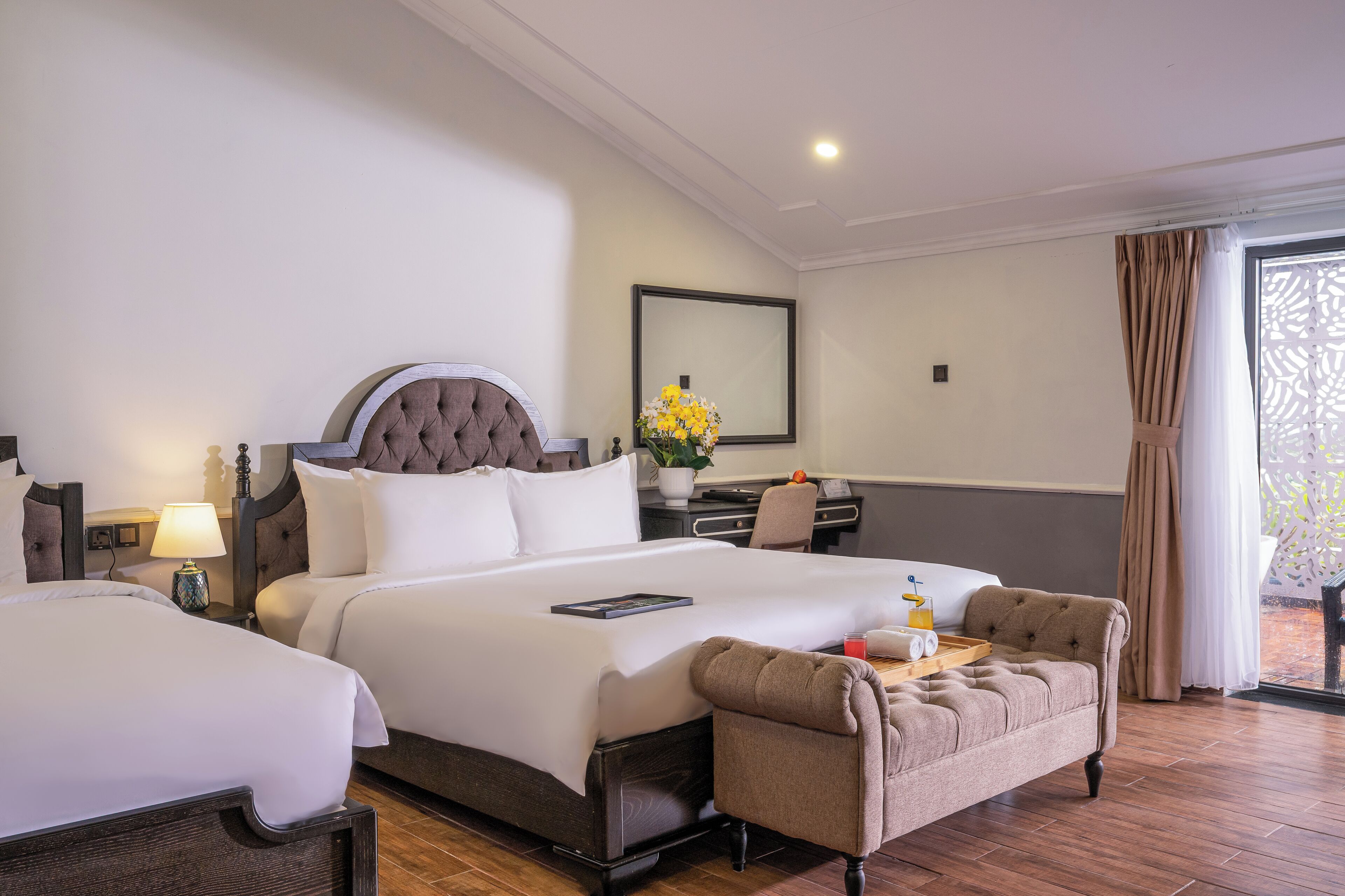 A hotel room with a large bed, a desk, a chair, and a small sofa.
