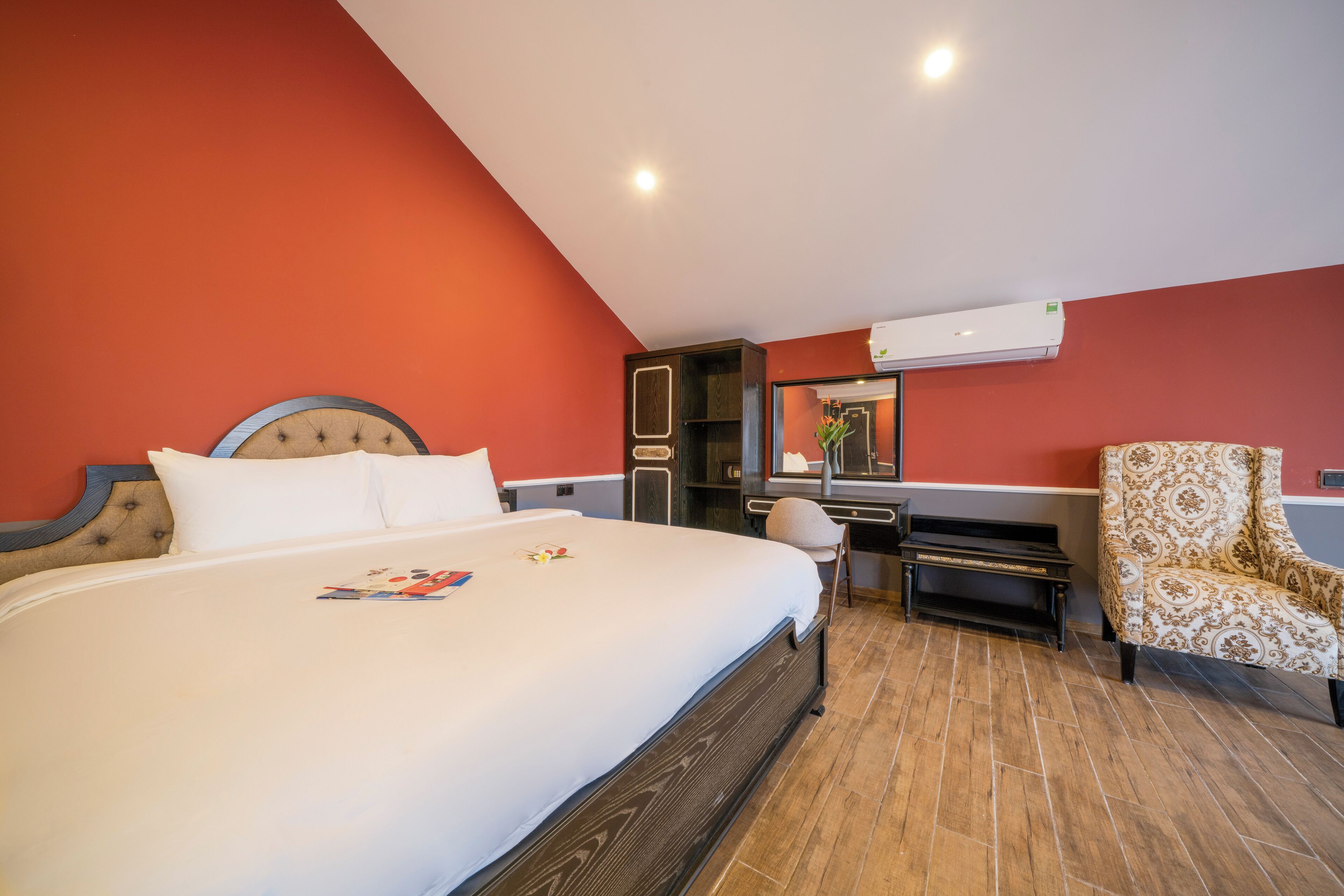 Une chambre d’hôtel avec un grand lit, un bureau, une chaise et un appareil de climatisation.