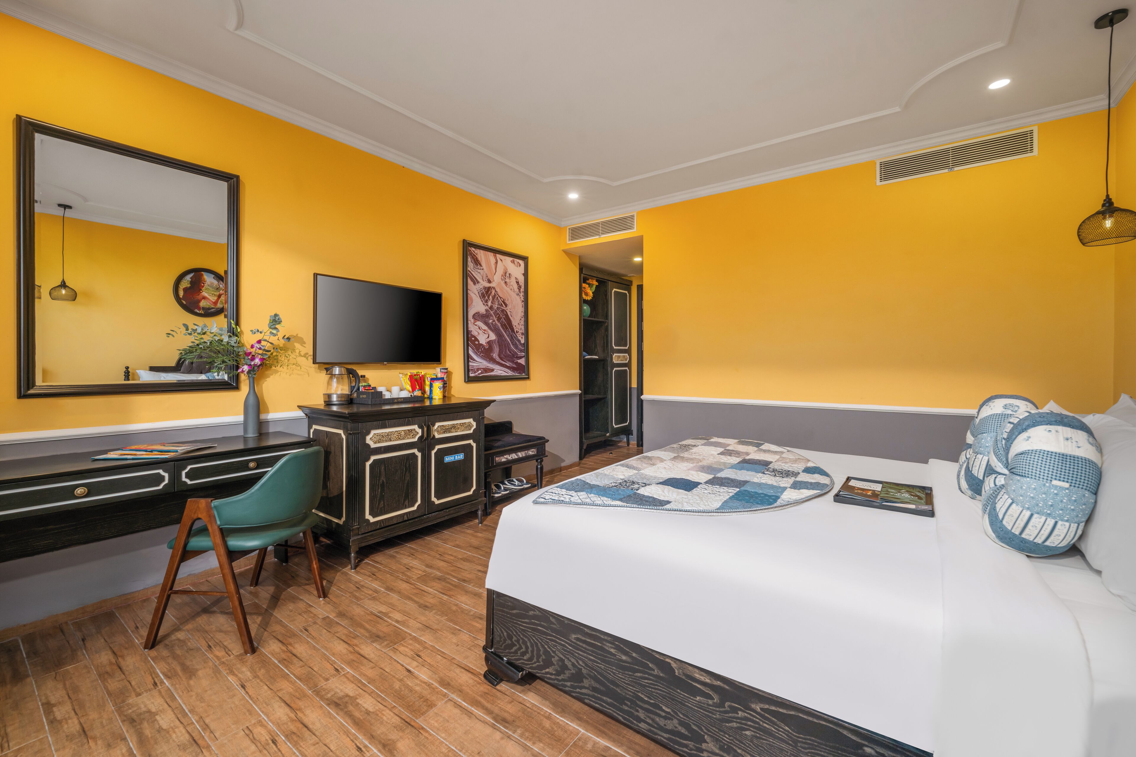 A hotel room with a bed, a desk, a chair, a television, and a large mirror.