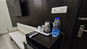 Een kleine kitchenette met een magnetron, waterkoker en waterflesjes op een aanrecht.