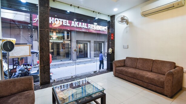Een hotelhal met een bank, een glazen tafel en uitzicht op de straat.