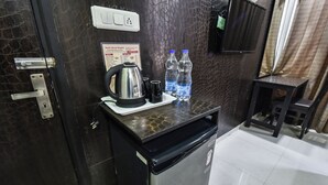 Een compact keukenhoekje met een koffiezetapparaat, twee waterflesjes en een klein tafeltje.