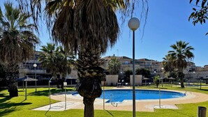 A swimming pool surrounded by palm trees and a building in the background.
