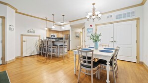 A dining area with a white table, blue placemats, and wooden chairs. - Breezy Beach | Villa 75 Steps from Lake Michigan (Sheboygan)