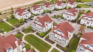 A residential area with white houses featuring red roofs, arranged in a grid pattern with a beach in the background. - Breezy Beach | Villa 75 Steps from Lake Michigan (Sheboygan)