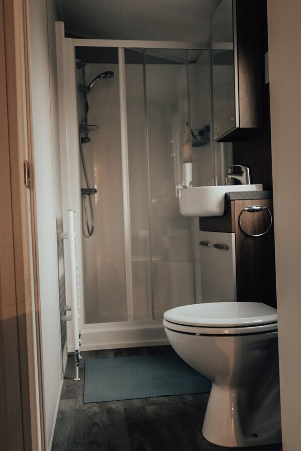 Une salle de bain comprenant des toilettes, un lavabo et un espace douche.