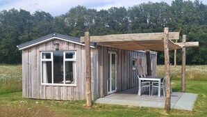 Une cabane en bois rustique dotée d’un patio couvert et d’une table à manger.