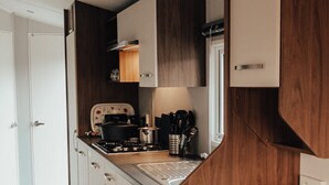 Une cuisine de taille réduite, avec des meubles de rangement en bois, une cuisinière et un évier.
